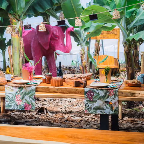 Lange Tafel für eine Gruppe zwischen den Bananenstauden, im Hintergrund der rosa Elefant der Finca